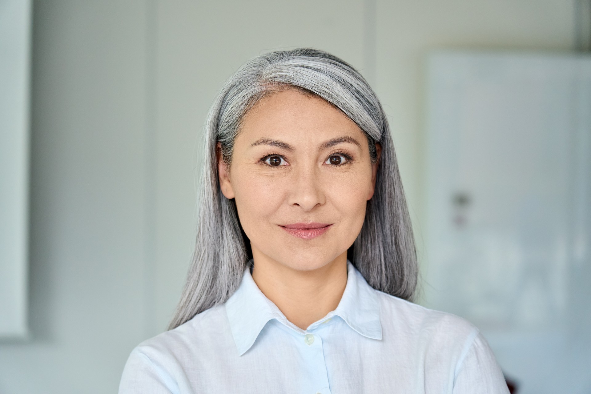 Happy confident middle aged Asian older senior female lawyer businesswoman corporation ceo in modern office looking at camera. Business woman executive concept. Closeup portrait headshot.